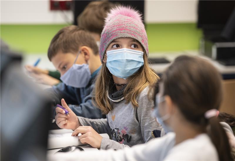 Mit Mundschutzmasken sitzen Schüler der fünften Klasse eines Gymnasiums im Unterricht, ein Mädchen trägt eine Mütze. Symbolbild: Boris Roessler, dpa