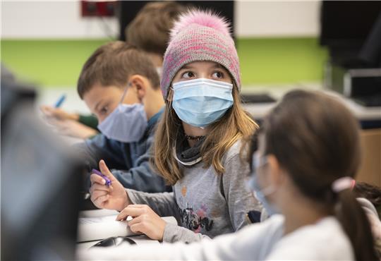 Mit Mundschutzmasken sitzen Schüler der fünften Klasse eines Gymnasiums im Unterricht, ein Mädchen trägt eine Mütze. Symbolbild: Boris Roessler, dpa