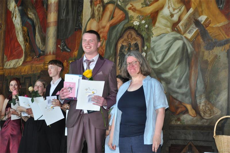 Mit Rose und Zeugnis stehen die Abiturienten auf der Kaiserpfalz-Bühne.