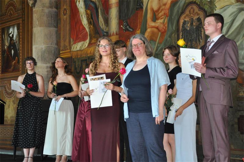 Mit Rose und Zeugnis stehen die Abiturienten auf der Kaiserpfalz-Bühne.