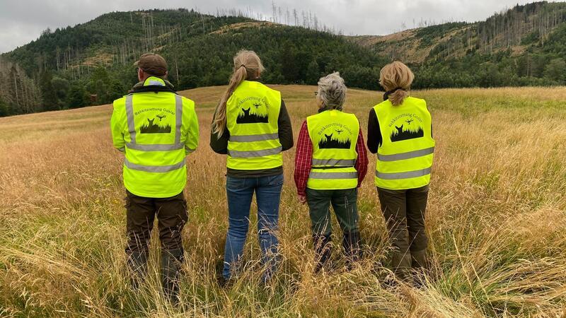 Einsätze zurückgegangen: Weniger Tiere vor dem Mähtod bewahrt Mit Signal-Westen ausgestattet: Rehkitzretter stehen vor einem Einsatz auf einer Wiese bei Oker.
