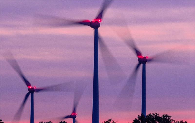 Branche fordert mehr Tempo beim Windkraft-Ausbau Mit Signallampen beleuchtete Windräder drehen sich nach Sonnenuntergang.