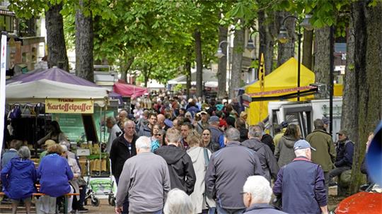 Zahlreiche Menschen schlendern eine Allee auf und ab. Neben ihnen sind Essens-Stände aufgebaut.