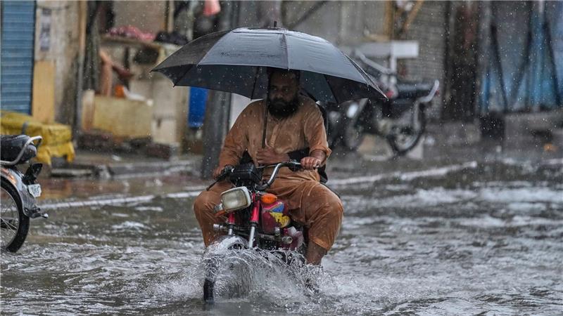 Bilder des Tages Mit aufgespanntem Regenschirm fährt ein Motorradfahrer waghalsig durch die Monsunfluten.