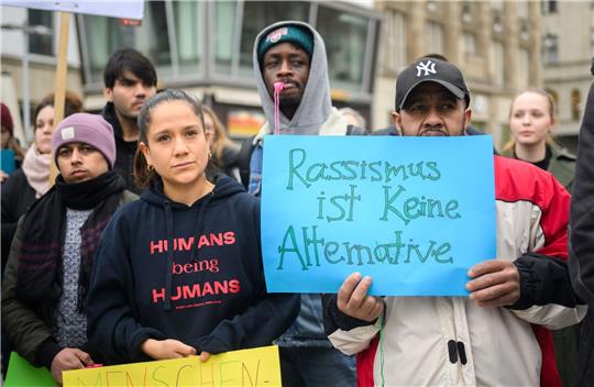 Mit beschrifteten Kleidungsstücken und Schildern demonstrieren Menschen bei einer Veranstaltung am Kröpke.