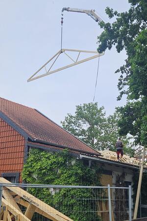 Sanierung nimmt Fahrt auf: Neues Dach für den Gielder Feier-Saal Mit einem Kran werden die Dachbinder auf die Außenmauern des Saals im Franz-Tasler-Haus gehievt.
