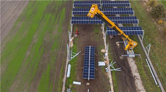 Mit einem Kran wird in Lüchow eine Agrar-Photovoltaik-Anlage montiert.