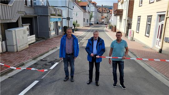 Mit einem symbolischen Scherenschnitt öffnen Bürgermeister Ralf Abrahms (Mitte), Sören Teuber vom Planungsbüro Conterra (l.) und Frank Woick vom städtischen Bauamt die Schmiedestraße wieder für den Verkehr.