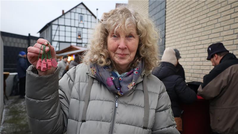 Eine Frau hält die rosa GZ-Glücksschweine hoch.