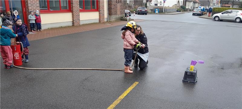 Spannende Einblicke in die Bad Harzburger Feuerwehr Mit einer Kübelspritze gehen die Kinder gegen einen imaginären Brand vor. Erzieherin und Feuerwehr-Gruppenführerin Nadine Wieczorek unterstützt die Jungen und Mädchen beim Löschen. Foto: Privat
