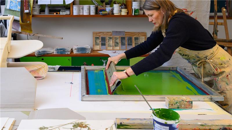 Botanik trifft Handwerk: Die neue Sehnsucht nach Naturkunst Mit einer Rakel verteilt Krieger die Farbe gleichmäßig auf dem Stoff.