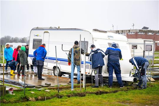 Mit gegenseitiger Unterstützung schieben die Urlauber ihre Wohnwagen auf die Parzellen.