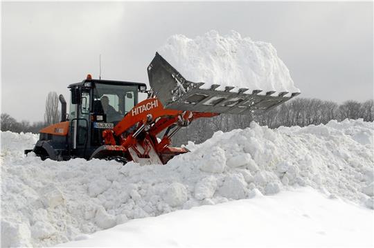 Mit schwerem Gerät rücken die Helfer dem Schnee zu Leibe und transportieren ihn zum Osterfeld.