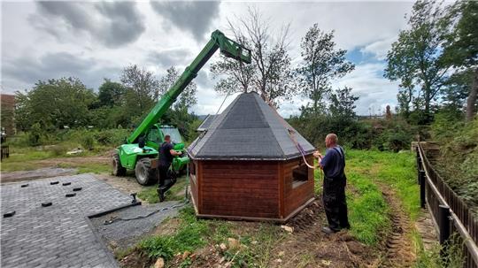Mit technischer Unterstützung der Firma Friehe wird die Hütte auf dem Rastplatz Wassermühle Hinze gleich an ihren endgültigen Standort gehoben – der gepflasterten Fläche daneben. Fotos: Privat