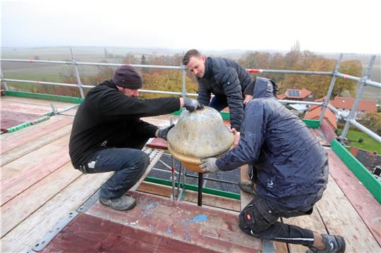 Mit vereinten Kräften schieben die Liebenburger Dachdecker die Kugel über das Gestänge der Bekrönung. Foto: Gereke