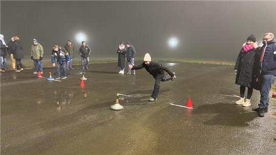 Mit viel Schwung schieben die Teilnehmer den Eisstock über den Asphalt.