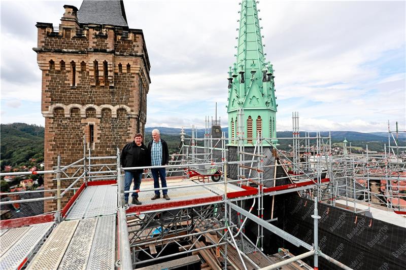 Mitarbeiter der beteiligten Baufirmen stehen auf einem Baugerüst über dem Schloss Wernigerode. Das Gerüst wurde für die Sanierung der Dächer an Kirchenschiff und Glockenturm benötigt. Es wird nun ab- und an anderer Stelle auf dem Grundstück wieder aufgebaut, die Sanierung läuft weiter.  Foto: Bein
