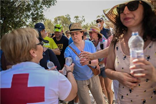 Mitarbeiter des Griechischen Roten Kreuzes verteilen vor der Akropolis Wasserflaschen an  Besucher.