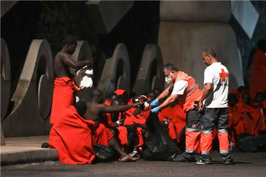Mitarbeiter des Roten Kreuzes verteilen im November Wasser an Migranten an einer Anlegestelle im Hafen von La Restinga auf der kanarischen Insel El Hierro.