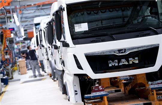 Mitarbeiter von MAN Truck & Bus arbeiten in einer Produktionsstraße.
