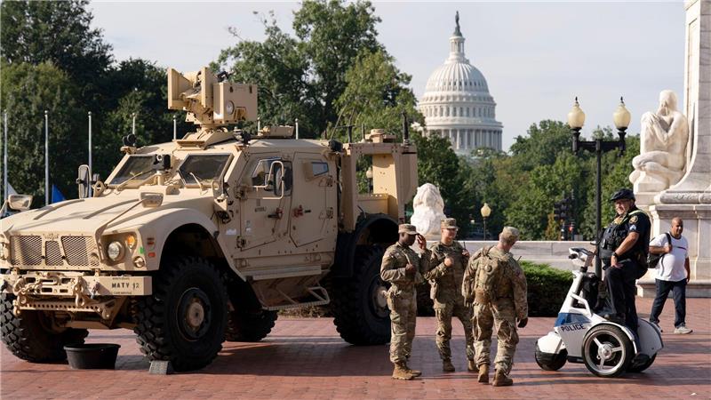 Mitglieder der Nationalgarde, die auf Anordnung von Präsident Trump in der US-Hauptstadt Washington sind, stehen neben einem gepanzerten Fahrzeug. 