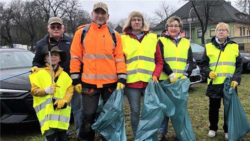 „Müllboss“ in Goslar: Skier, Auspuff und „Drogen“ im Müll entdeckt Gruppe von sechs Personen mit Warnwesten und Handschuhen steht auf Grasfläche vor parkenden Autos und hält Müllsäcke und Greifzangen.