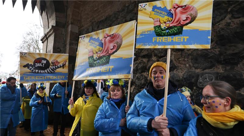 Die Rosenmontagszüge rollen: Putin und die Macht der Narren Mitglieder des ukrainischen Hilfsvereins Blau-Gelbes Kreuz halten im Kölner Rosenmontagszug Plakate mit früheren Putin-Darstellungen aus den Zügen in Köln und Düsseldorf hoch.