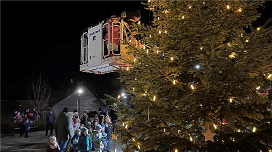 Mithilfe der Drehleiter und von Kinderfeuerwehrwart Lennart Lohmann bringen die Kinder die selbst gebastelten Weihnachtssterne am Weihnachtsbaum an.