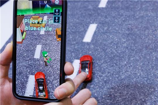 Mittels Smartphone, welches ein reales Spielzeugauto mit der Kamera erfasst, wird beim Spiel «Zombie Crasher AR» von Augmented Robotics eine virtuelle Straßenszene dargestellt.