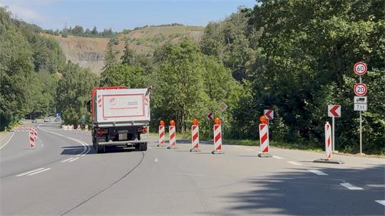 Ein lkw fährt eine breite, aber steile Straße hinunter, auf der eine FAhrspur gesperrt ist.