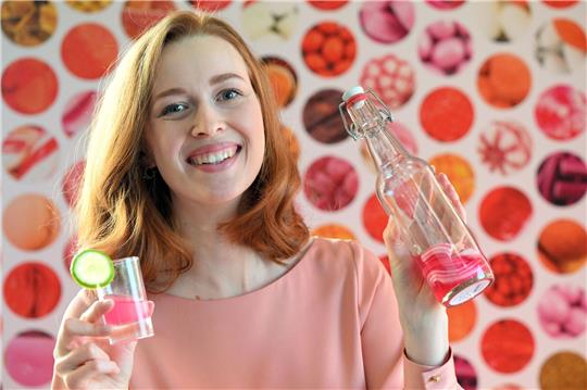 Model Christin hält auf der  Internationalen Süßwarenmesse ein Glas Wodka in der Hand, das mit Sweet Shots-Bonbonmasse versetzt wurde.
