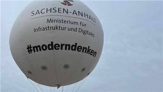 Ein Ballon mit der Aufschrift "Modern denken" ist zu sehen. Darüber das Landeswappen von Sachsen-Anhalt.