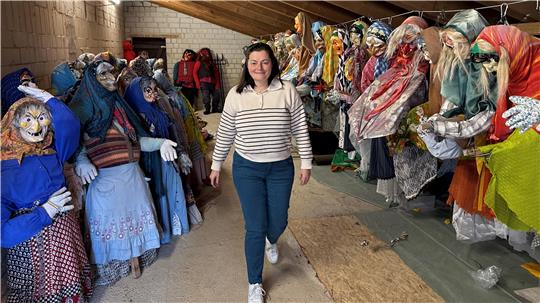 Das Foto zeigt eine Frau, die an vielen Teufel- und Hexenpuppen vorbeigeht.