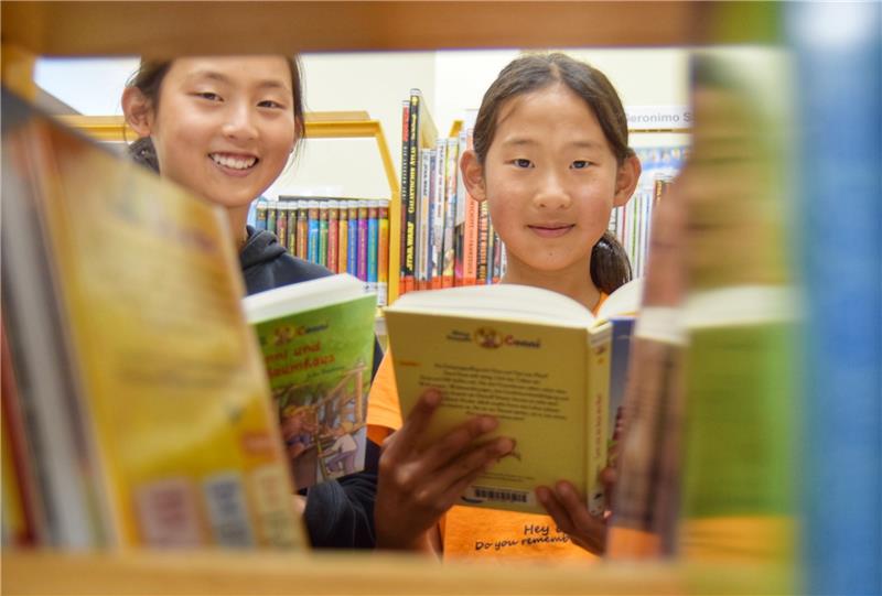 Monika Yu (rechts) und ihre Schwester Christine verbringen ihre Freizeit am liebsten in der Stadtbibliothek. Vor allem in den Sommerferien nutzen sie jede freie Minute, um zu lesen. Foto: Neumann
