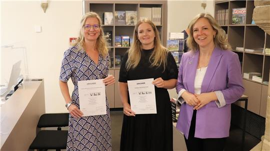 Morea Deden, Marketing-Leiterin der Stiftung Welterbe im Harz, Lea Dirks, wissenschaftliche Mitarbeiterin der Welterbe-Stiftung und Judith von Hof, Leiterin der Tourist-Info (von re.) mit den Zertifikaten. Hier sorgt ein zusätzlicher Counter in der idealen Höhe für Rollis (links im Bild) für inklusiven Gäste-Service. Foto: Kaspert