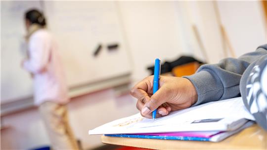 Eine Schülerin schreibt etwas auf ein Blatt Papier.