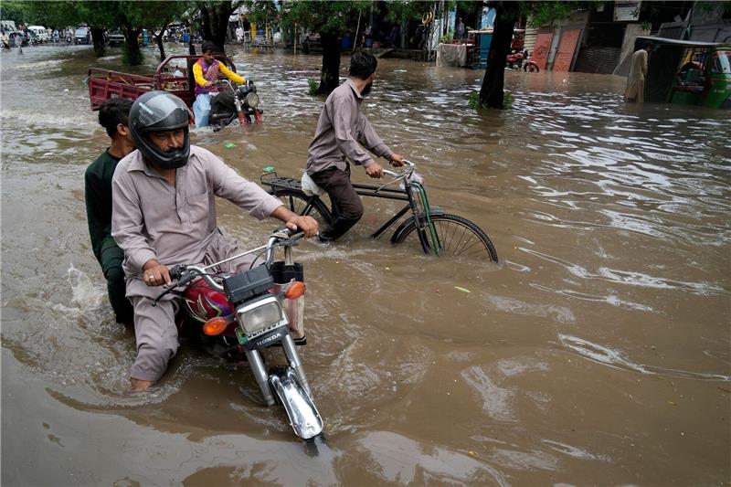 Dutzende Tote bei erstem Monsunregen in Südasien Motorradfahrer auf einer überschwemmten Straße im pakistanischen Lahore.