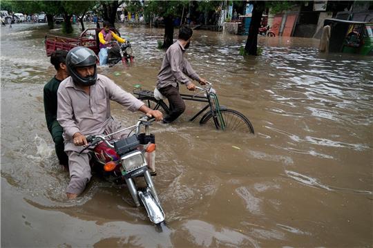 Motorradfahrer auf einer überschwemmten Straße im pakistanischen Lahore.