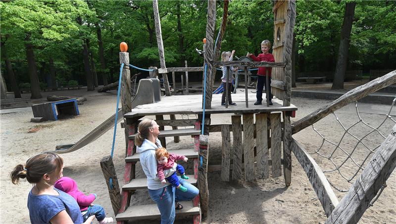 Blick auf einen Kinderspielplatz, auf denen sich Mütter mit Kindern aufhalten.