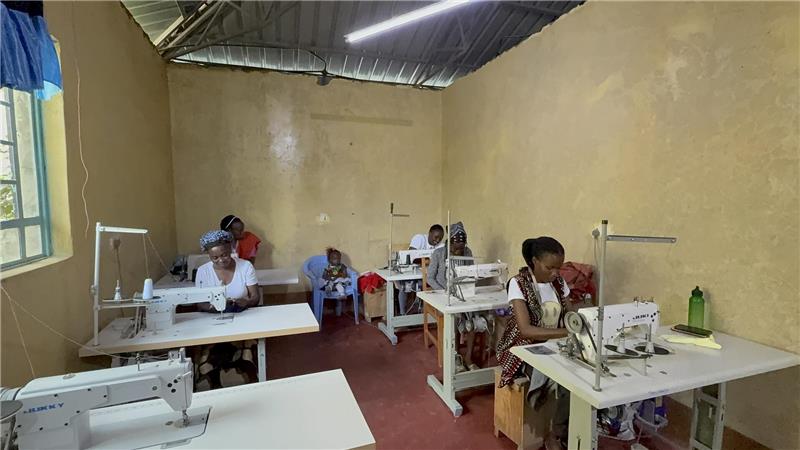 Mütter nähen im Center, während ihre Kinder nebenan unterrichtet werden.