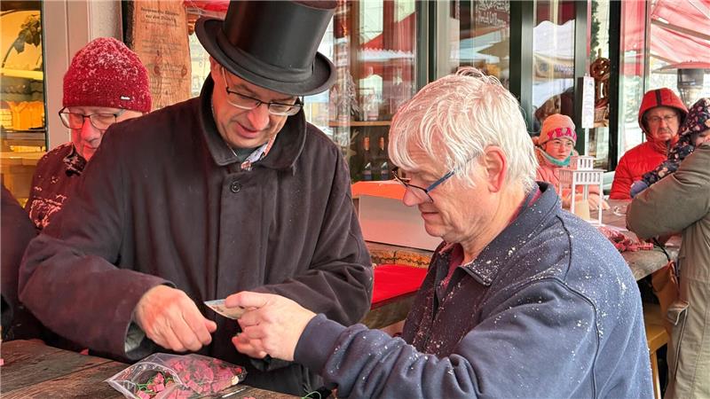 Ein Mann verkauft einem anderen Mann Glücksschweinchen.