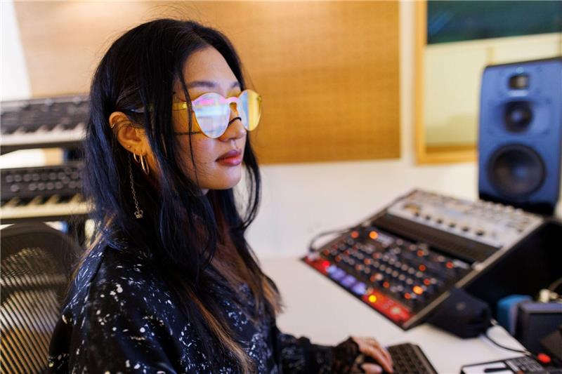 Musikerin Rania Kim zwischen Displays, Anlagen und Instrumenten in einem Studio in Berlin.