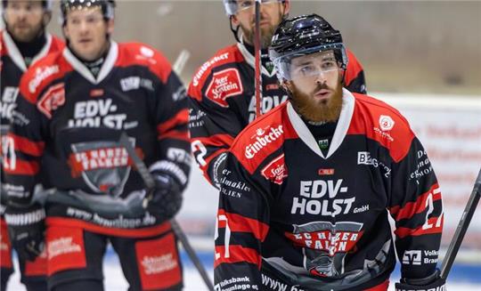 Eishockeyspieler in schwarzen und roten Trikots mit Werbeaufschriften auf dem Eis, alle halten einen Schläger in der Hand