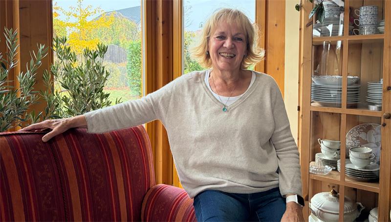 Das Foto zeigt eine Frau in ihrem Wohnzimmer.