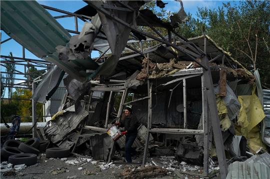 Nach dem russischen Raketenangriff löscht ein Mann in Saporischschja die Überreste eines Feuers in einer zerstörten Autowerkstatt.
