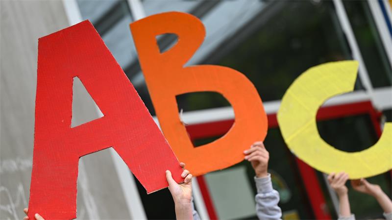 Kinderhände halten die Buchstaben A, B und C hoch.
