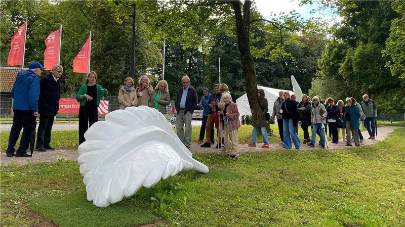 Oberharz: Warum liegen am Pulverhaus jetzt riesige weiße Federn? Nach der Einweihung des Skulpturenpfades erläutert Künstlerin Sina Heffner (3.v.l.) den Gästen die weißen Federn.