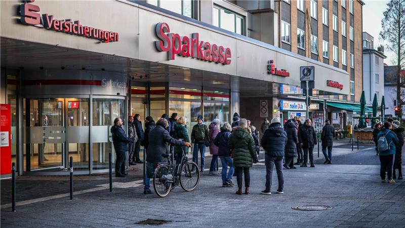 Nach einem Einbruch in den Tresorraum einer Bankfiliale in Gelsenkirchen warten Menschen vor dem Eingang auf Informationen.