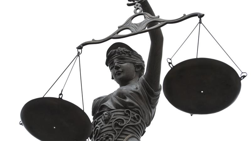 Eine Statue der Justitia hält eine Waage in ihrer Hand. 