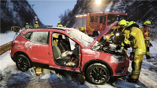 Einsatzkräfte der Feuerwehr beugen sich über den Motorraum eines Unfallwagens.